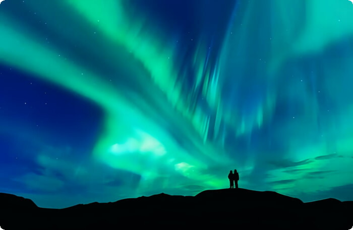 Пара наслаждается красочным северным сиянием в Исландии