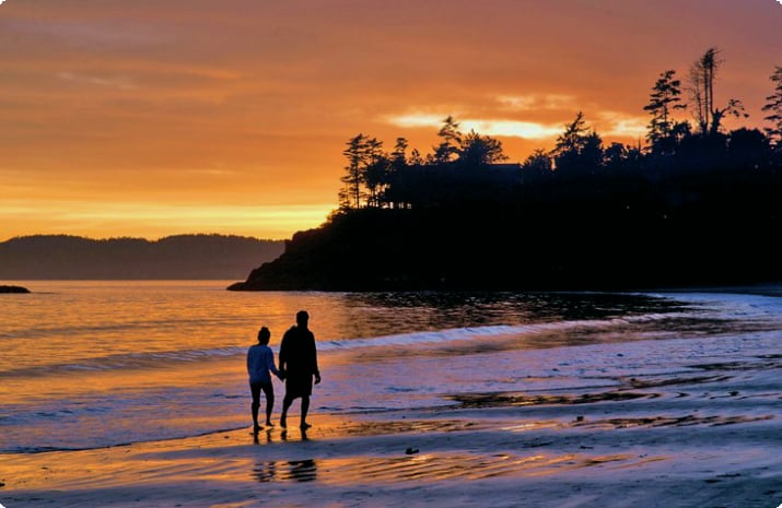 Пара гуляет по пляжу на закате в Тофино, Британская Колумбия