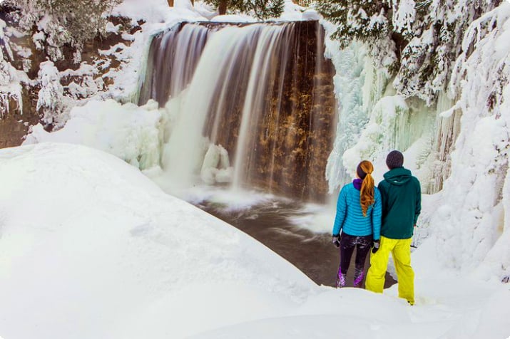  Par som njuter av ett vattenfall nära Whistler på vintern