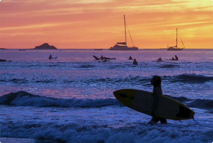 Силуэты серферов на закате на пляже Тамариндо