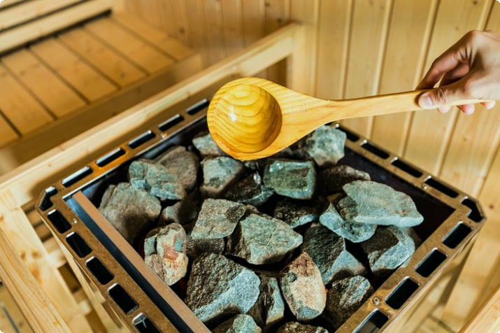 Wasser über heiße Steine in einer Sauna gießen