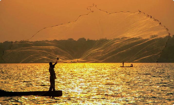 Pescatore che getta la rete al tramonto sul Lago Vittoria